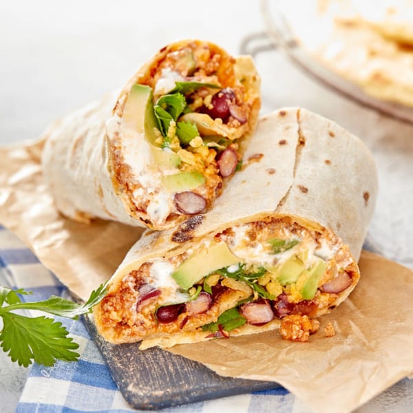 Two halves of a Yallah Taco burrito filled with beans, avocado, and sour cream.