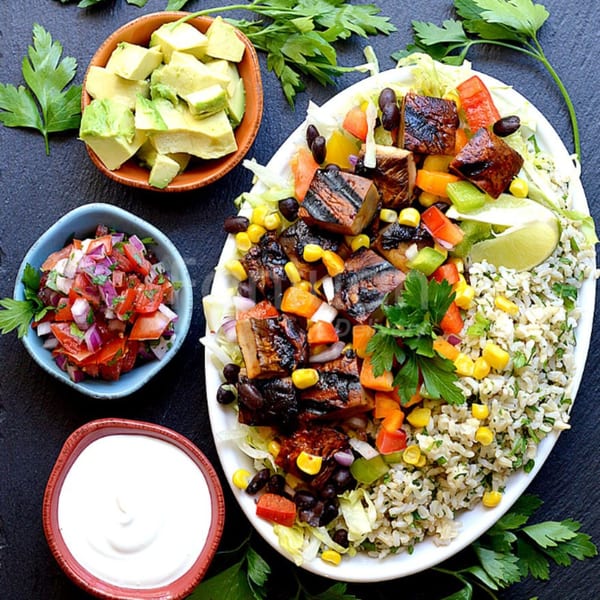 Yallah Taco's Mexican bowl with grilled meat, rice, beans, corn, salsa, avocado, and sour cream.