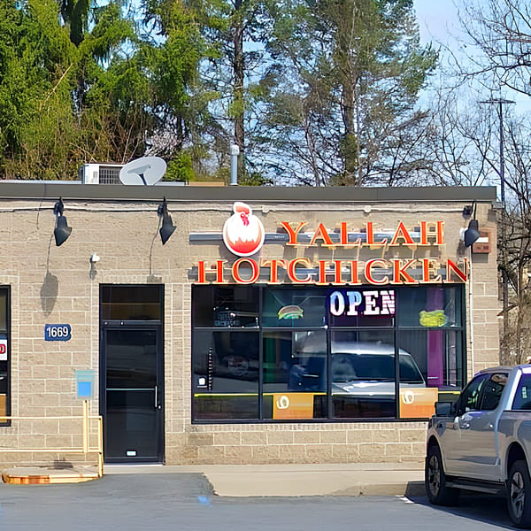 Exterior of Yallah Taco, a brick building with "Yallah Hotchicken" in red neon, and an "OPEN" sign.