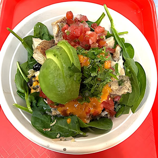 Yallah Taco's colorful Mexican bowl with chicken, spinach, avocado, salsa, and orange sauce.